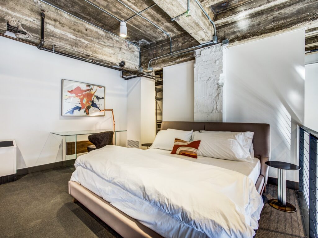 Upstairs loft bedroom, decorative stone pillar, exposed wooden rafter, and wooden ceiling.