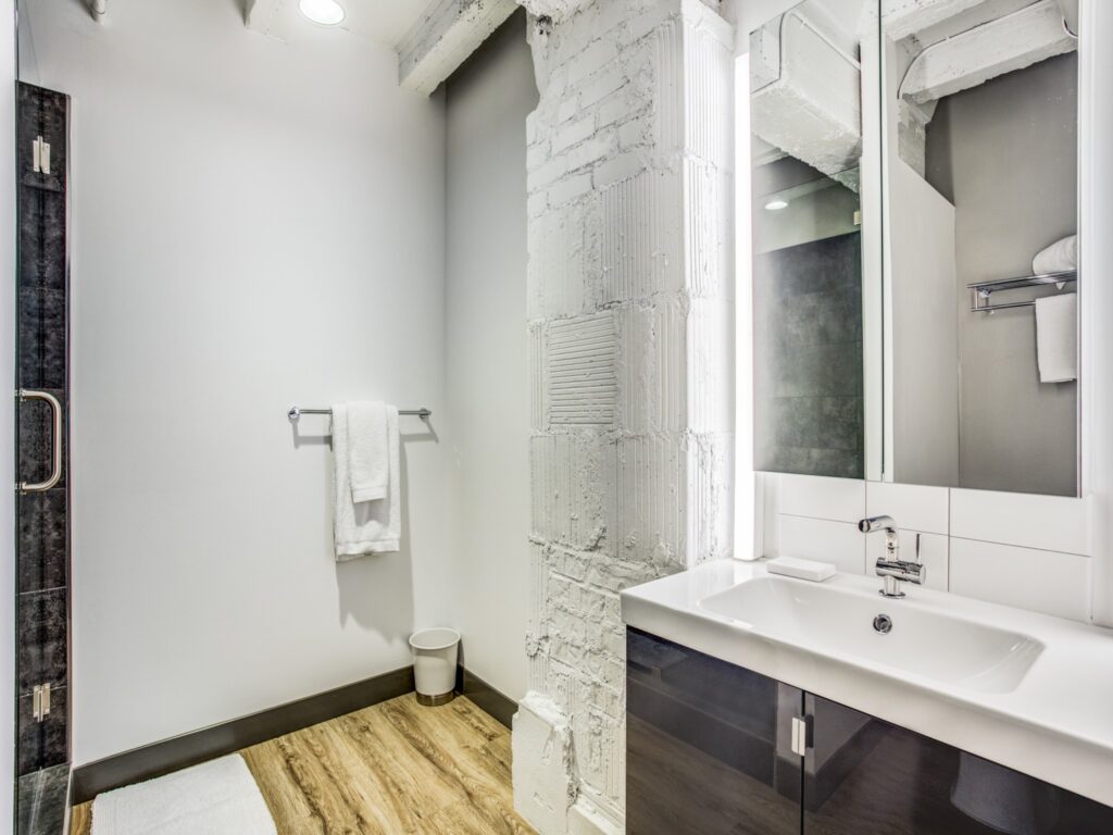 Bathroom withsingle vanity sink, hardwood flooring, and decorative stone pillar.
