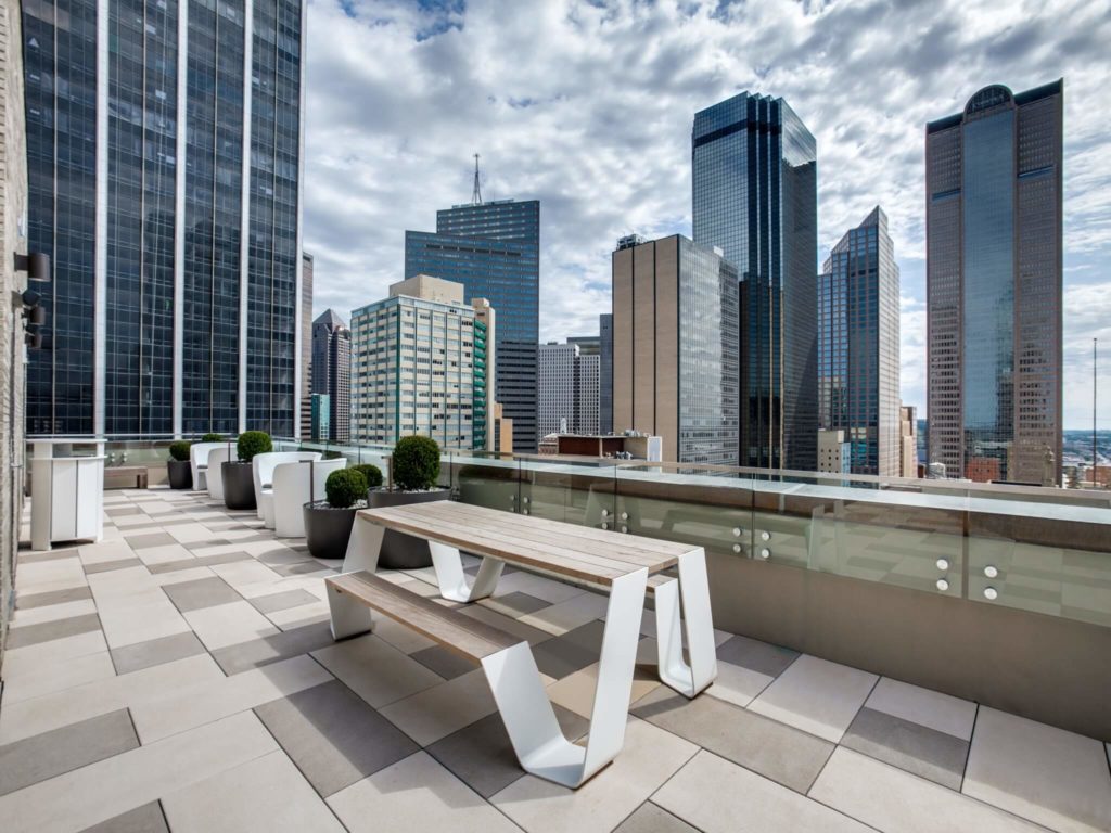 Outdoor seating area with modern picnic-like tables, stunning downtown views, and modern landscaping