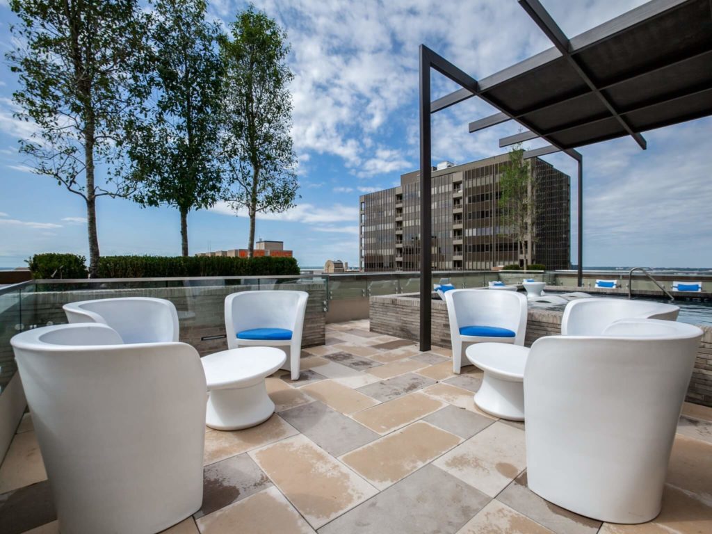 Rooftop patio area with modern chairs and tables and covered pool area