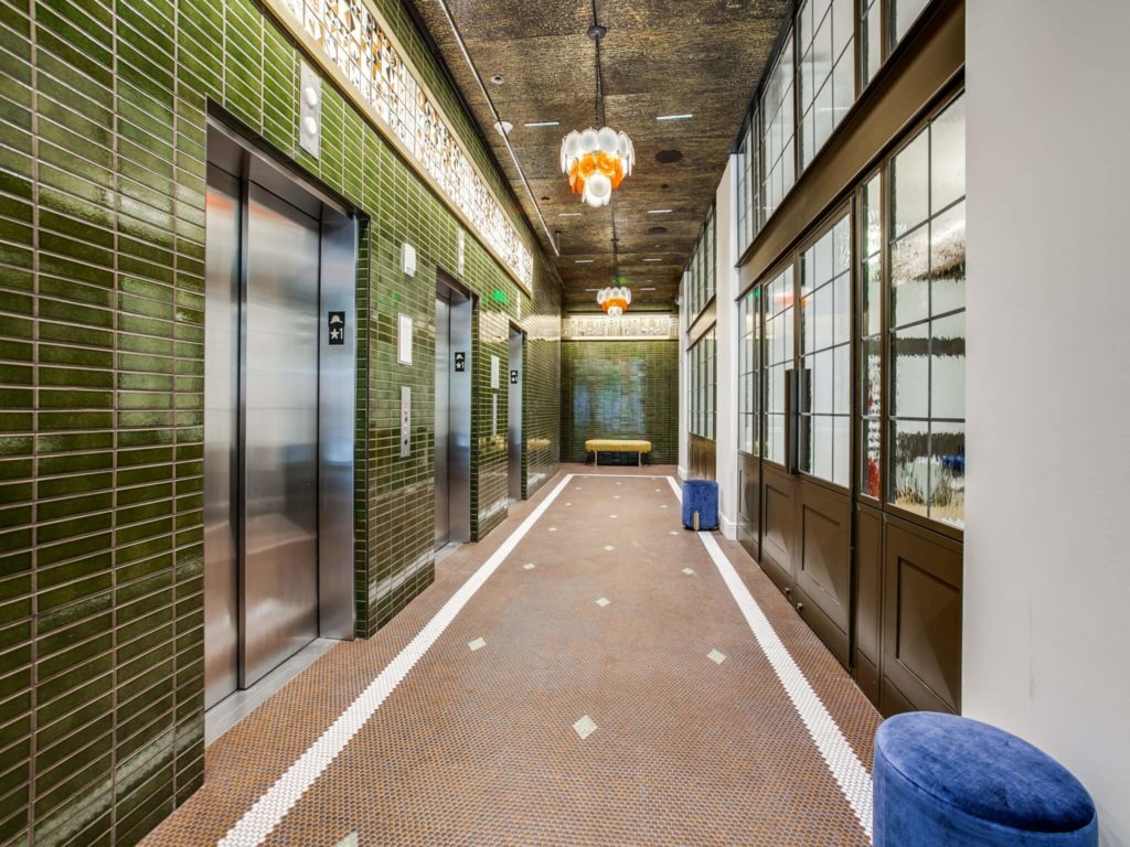 Elevator lobby with decorative tile floors and walls, designer lighting, and 3 elevator bays